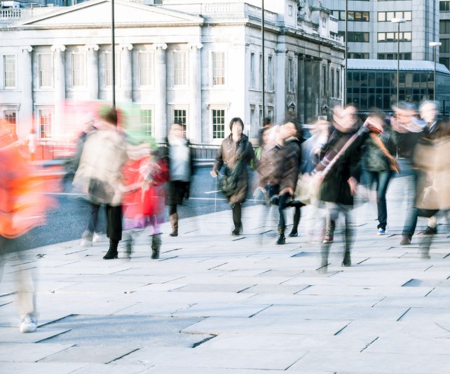 People with coats and scarves on commuting in London